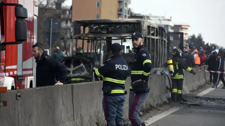 Firefighters and police officers stand by the gutted remains of a bus in San Donato Milanese, near Milan, Italy, March 21, 2019. Italian authorities say a bus driver transporting schoolchildren stopped his vehicle on a provincial highway, told the passengers to get off and then doused the interior with gasoline and set it on fire. Italian media reported that the driver, an Italian of Senegalese origin, was immediately apprehended. (Daniele Bennati/ANSA via AP)