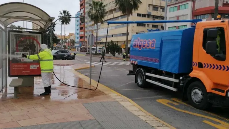 Un operario desinfecta una marquesina de la Acera de la Marina.