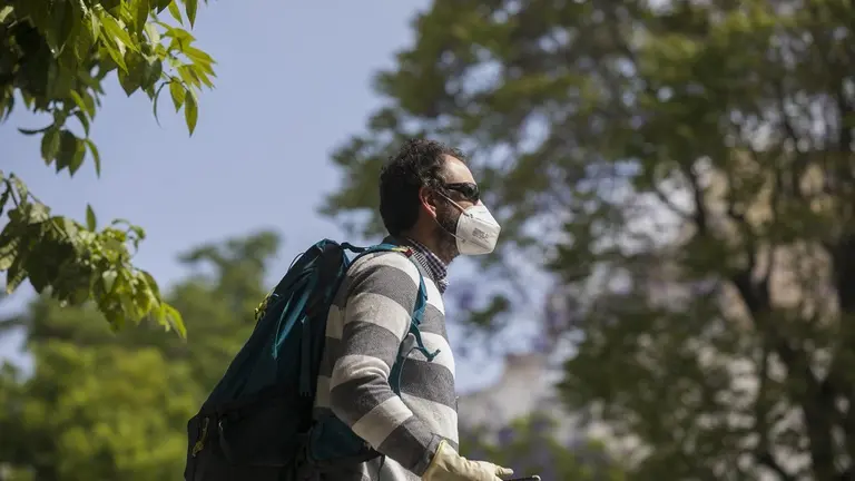 Un hombre camina con guantes y mascarillas.