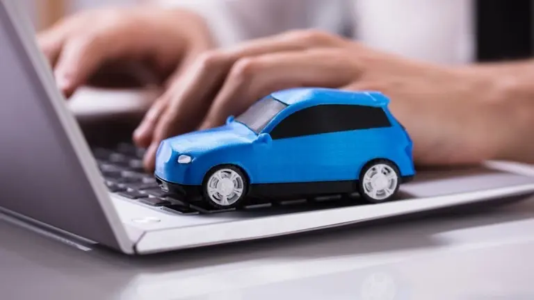 Close-up Of A Small Blue Car On Laptop Keypad