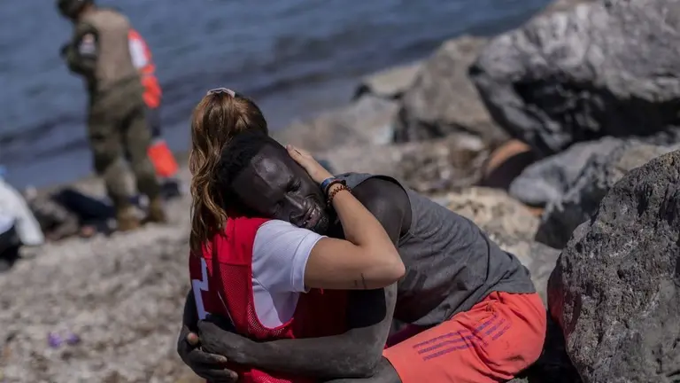 una voluntaria de cruz roja consuela a un inmigrante en el tarajal